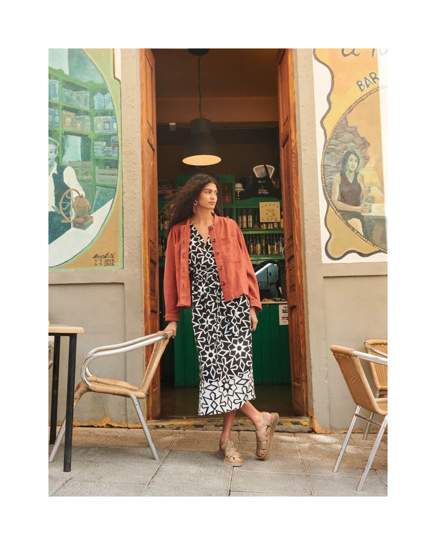 Woman wearing a linen jacket leaning in a doorway